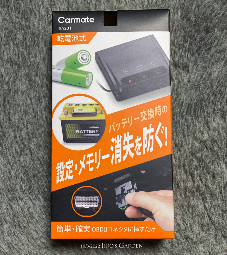 Carmate のメモリーキーパー SA201 のパッケージ写真。オレンジと黒のはっきりとしたデザイン。「バッテリー交換時の設定・メモリー消失を防ぐ!」のコピーが中央に大きくかかれている。サブコピー「簡単・確実 OBDIIコネクタに挿すだけ」乾電池式。