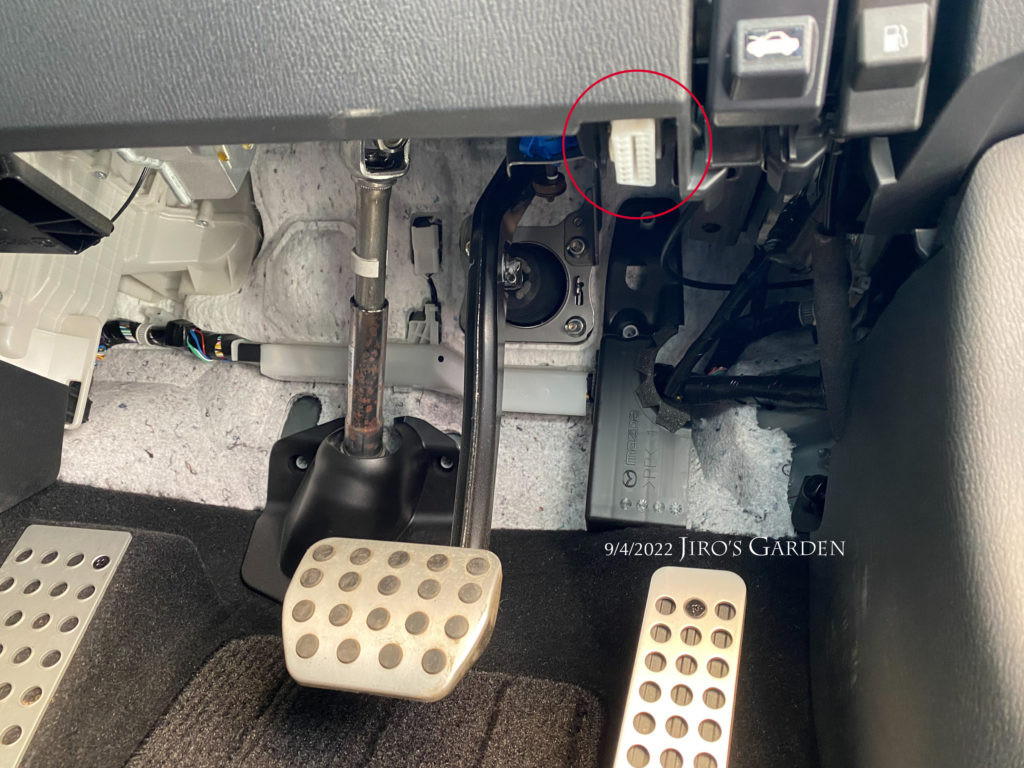 運転席下面からペダル類の部分を撮影。燃料タンクの蓋スイッチ、ボンネットスイッチの隣に上から見えないようにOBDIIのコネクタがある。
