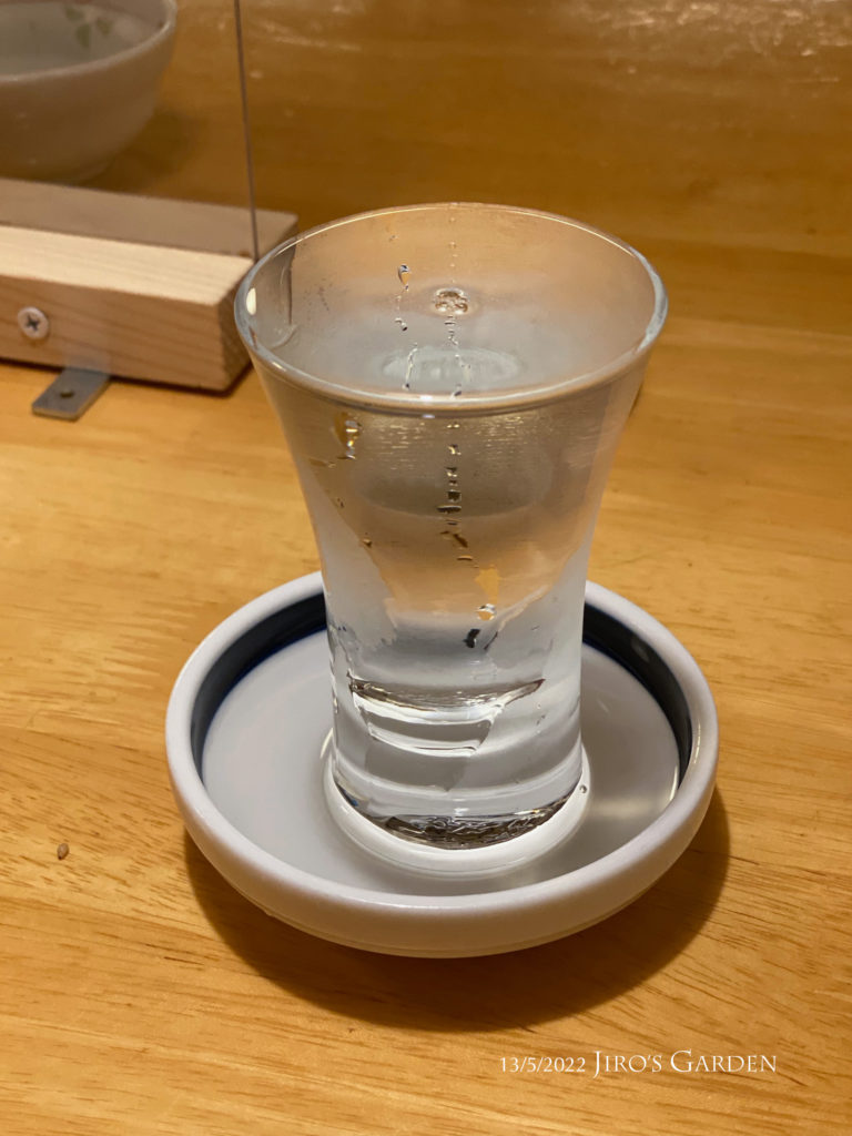 透明のグラスに白い受け皿の日本酒