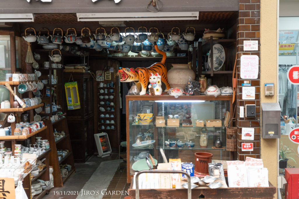 天井一面に吊るされた急須、ウインドウケースの上に置かれた大きなトラの人形、インパクトのある店内の様子。「福島 米・陶器店」