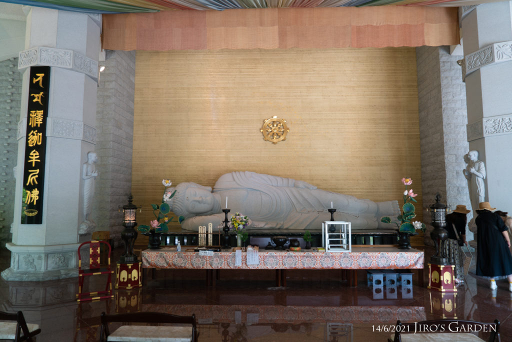 仏塔内部、長さ６m程の横たわった涅槃像と祭壇、右側に見学者数名。
