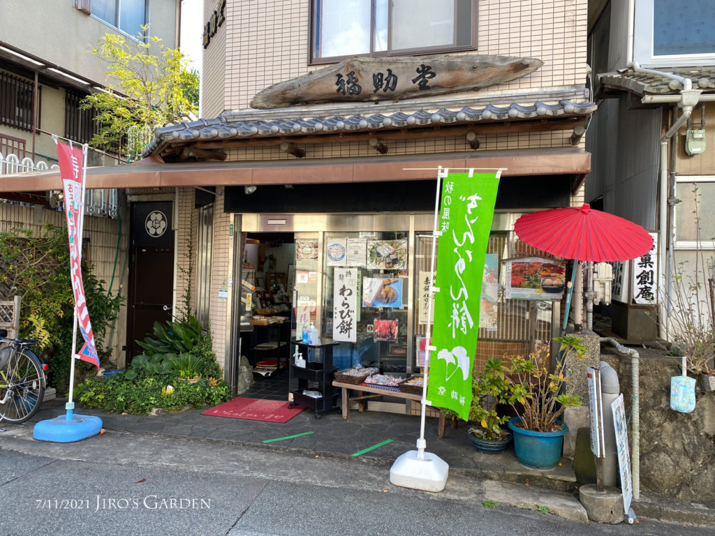 和菓子店福助堂の店舗外観。幟旗2本に赤い番傘、奇麗に手入れしてある植栽など、良い雰囲気。